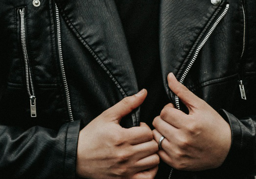 A closeup of a man holding his leather jacket