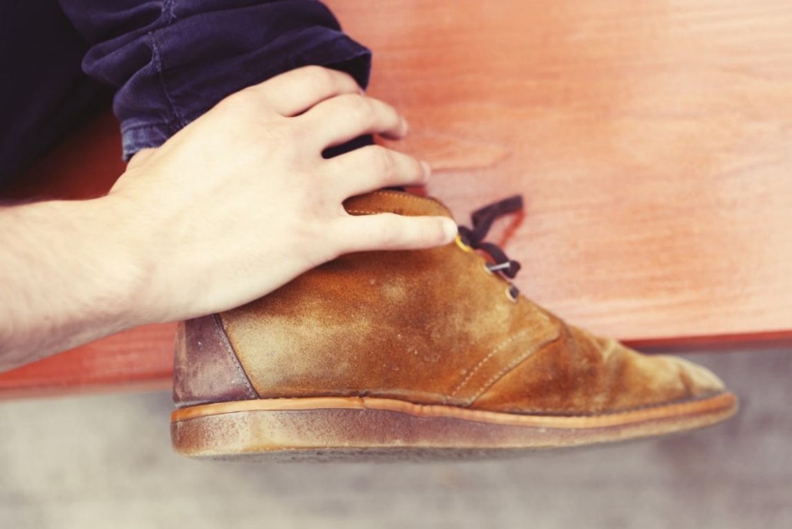 A closeup of a person wearing clean brown suedes