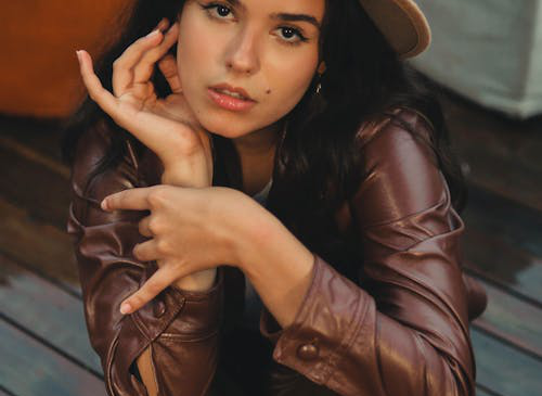 A woman wearing a brown leather jacket with pants and a hat