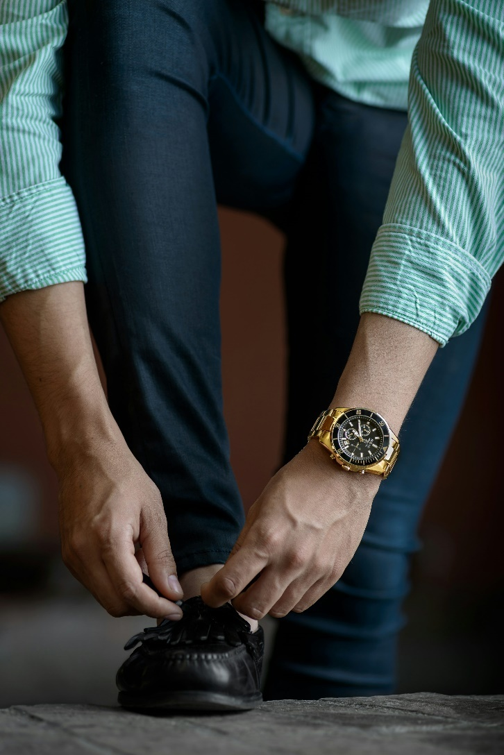  A man wearing a wristwatch tying his shoelace