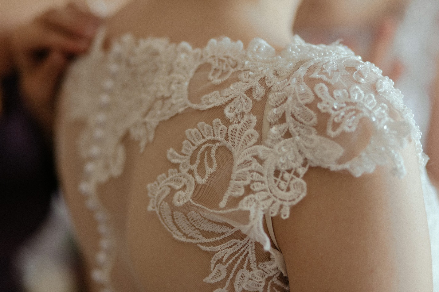 A closeup of a woman wearing a white sheer lace wedding gown